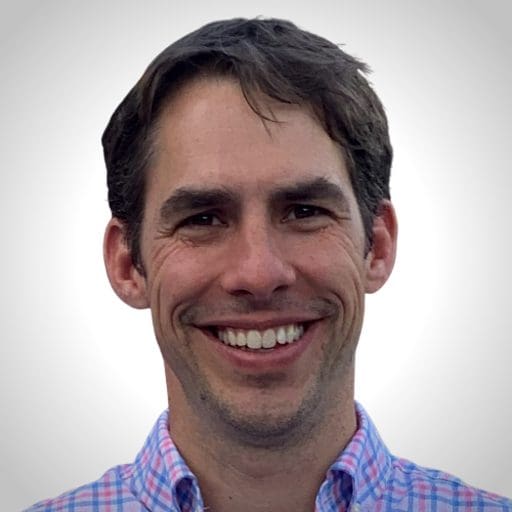 Portrait of Daniel Gehant smiling, wearing a plaid shirt.