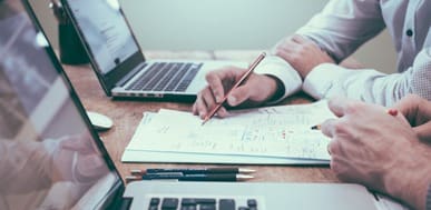 Two colleagues reviewing documents and laptops in a business meeting.