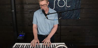 Man playing keyboard and singing into a microphone for a live performance.