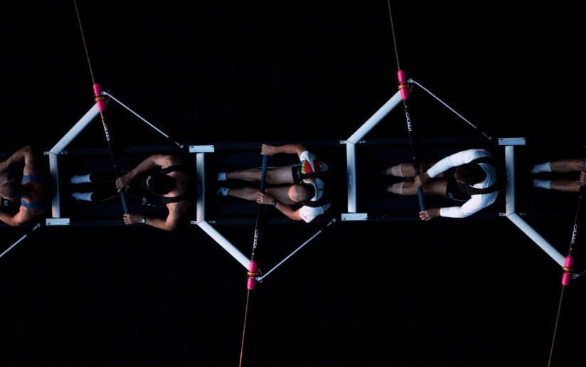 Rowing team in sync, top-down view. Illustrates teamwork skills for consultants.