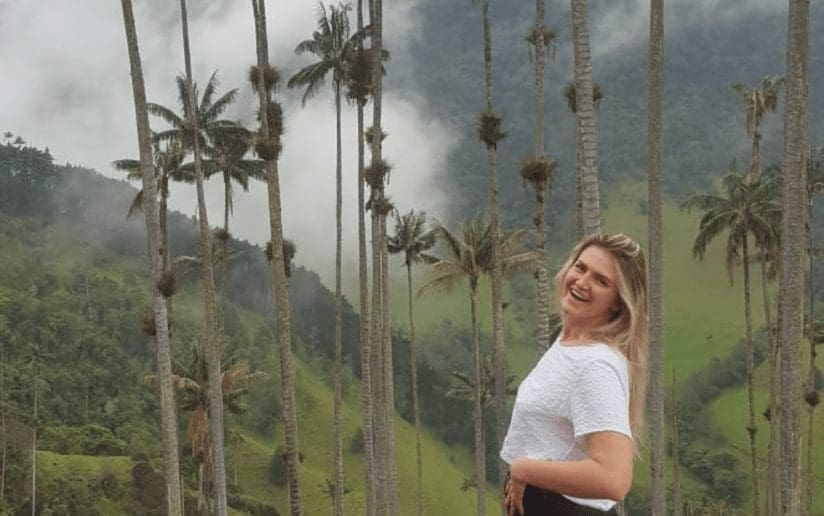 Amelia Clay smiling among tall wax palm trees in Cocora Valley, Colombia.