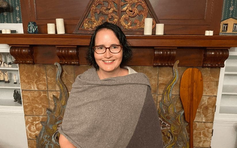 Kelly Saturno, driving positive social impact, smiles in front of a decorative fireplace.