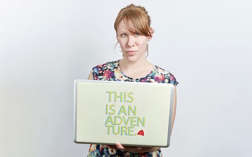 Woman holding sign that reads "This is an Adventure.