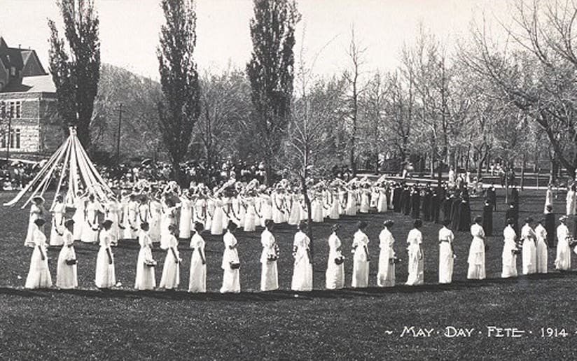 May Day Fete, 1914. Women in white dresses dance around a maypole on a grassy field.