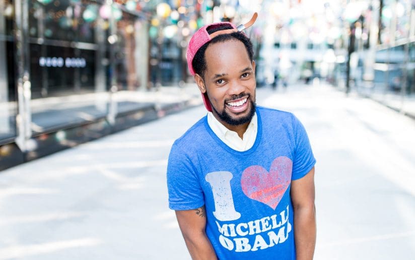 Michael Sanders wearing an "I Love Michelle Obama" shirt, smiling outdoors.