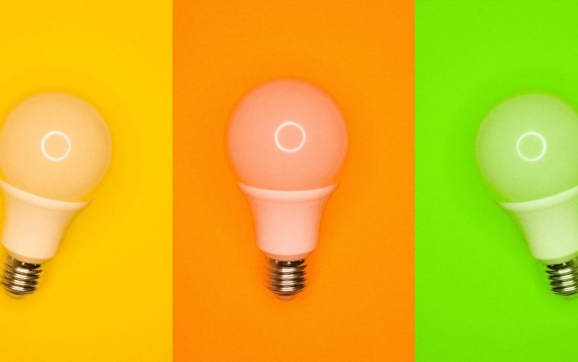 Three lightbulbs glowing in yellow, orange, and green, representing campaign testing for demand generation.