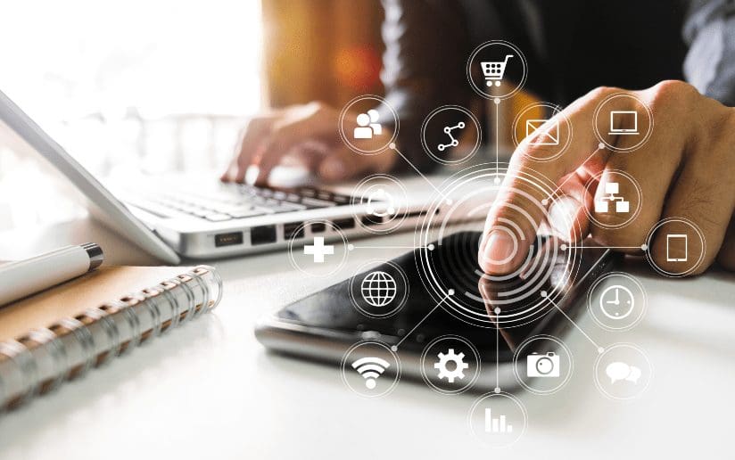 Person using a smartphone with digital marketing icons overlayed, laptop in background.