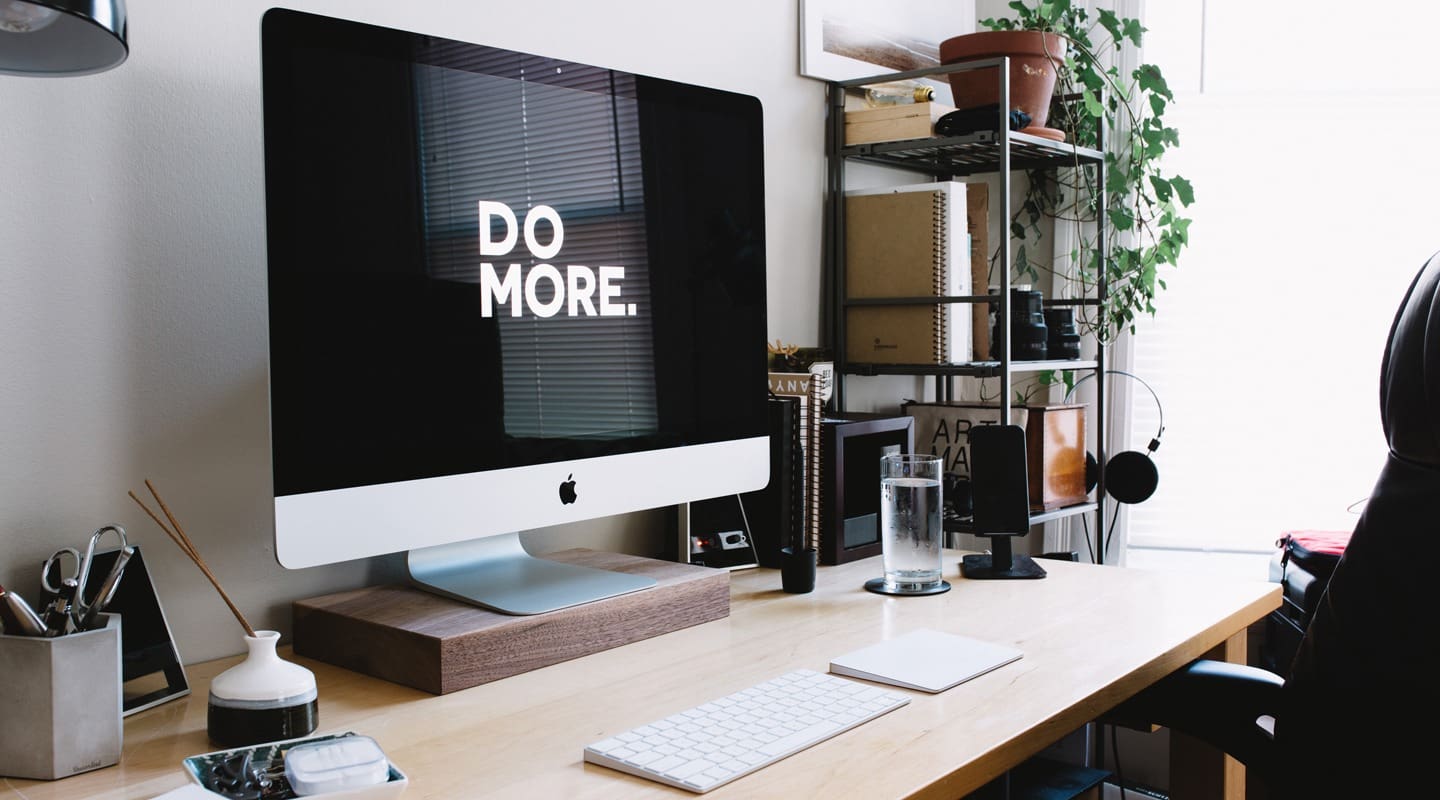 Workspace with Apple computer showing DO MORE on screen.