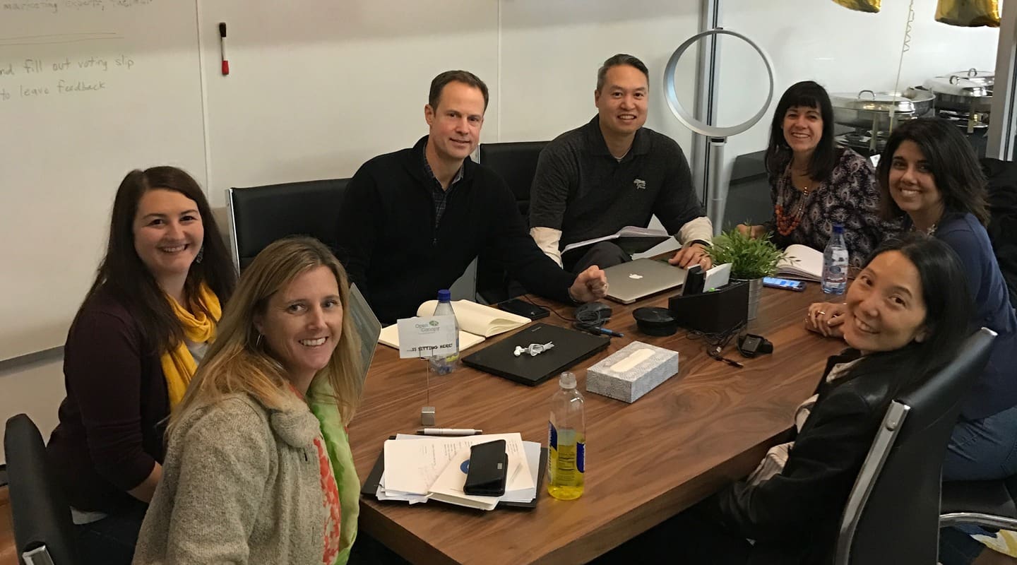 EM Marketing team meeting around a conference table, discussing strategy and feedback.