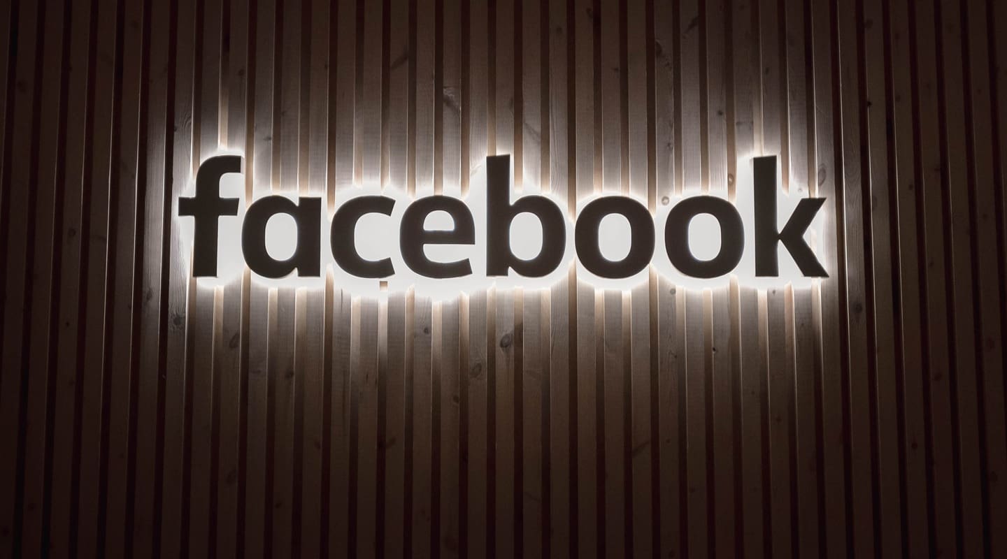 Facebook logo illuminated on a wooden wall