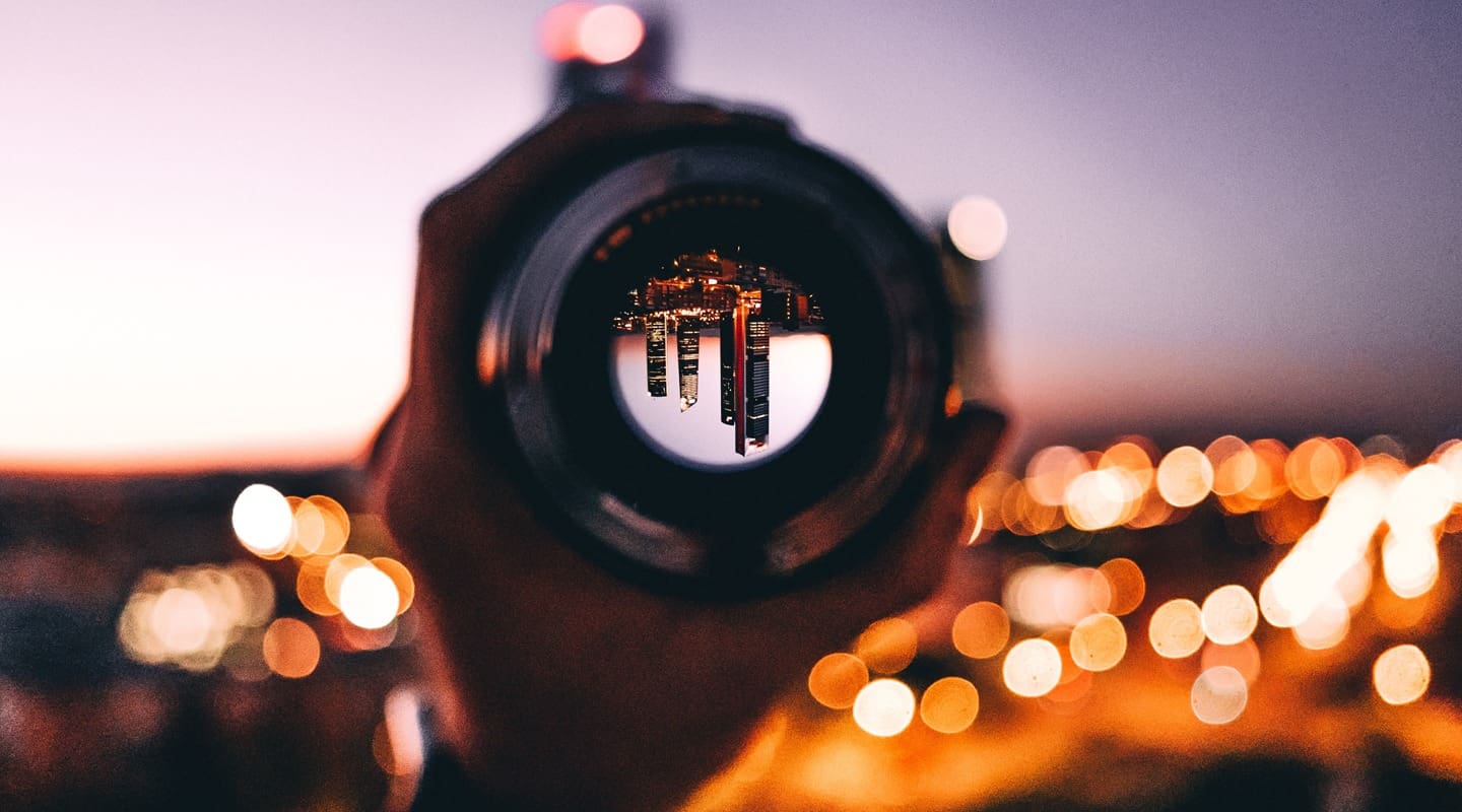 City skyline viewed through a camera lens at dusk, focusing on tall buildings. A pivot in the employment world.