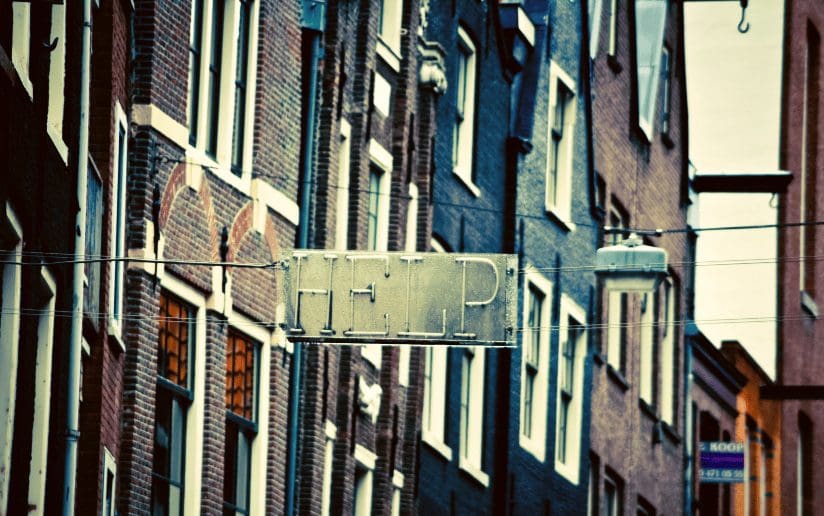 Sign reading "HELP" hanging between buildings in a city
