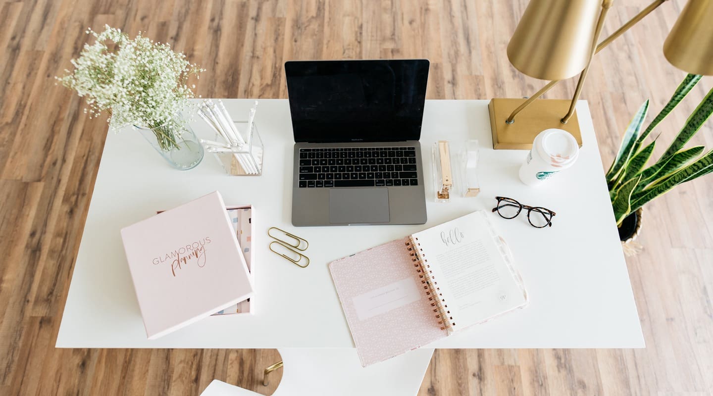 Stylish home office workspace with laptop, planner, and flowers. Glamorous planning.