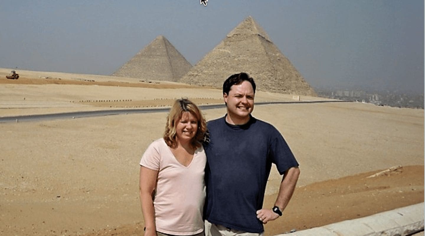 Couple poses in front of the Great Pyramids of Giza, Egypt.