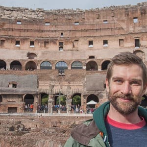 Man smiling in front of the Colosseum in Rome, Italy
