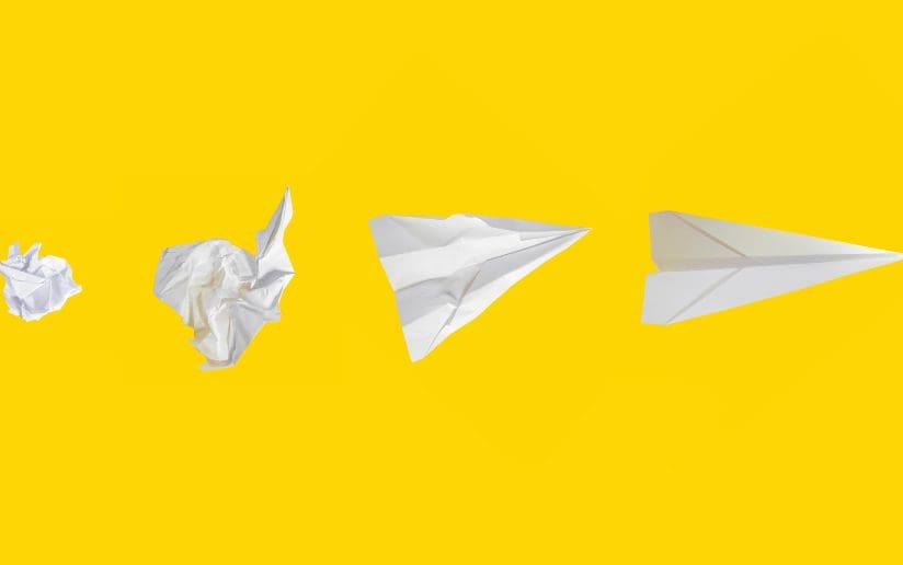 Paper airplane evolution: crumpled paper, unfolded paper, and finished paper airplane.