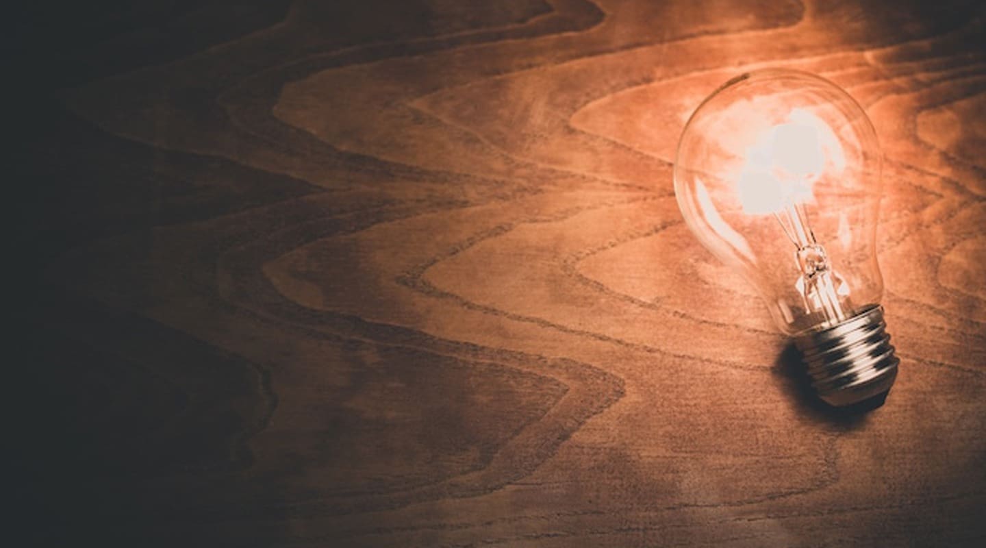 Glowing lightbulb on wood, symbolizing ideas and thought leadership.