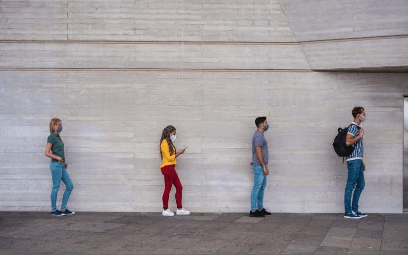 People socially distancing in line, wearing masks during the pandemic.