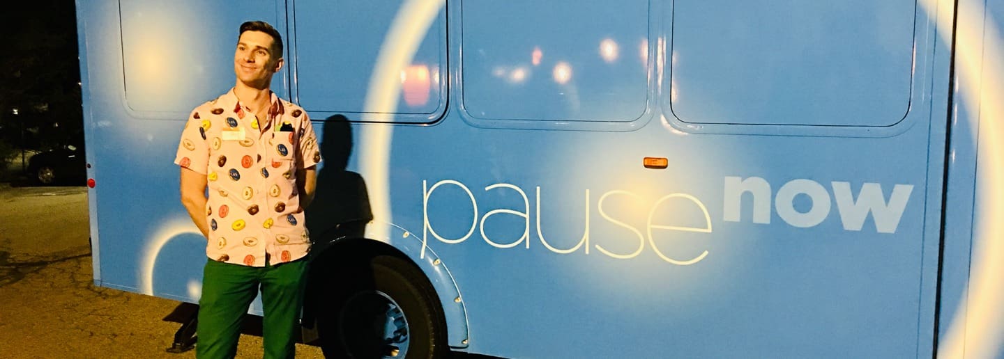 Man in donut shirt stands by pause now bus. Reflecting on the buyers journey.