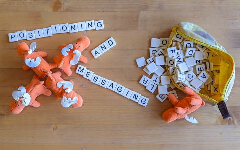 Scrabble tiles spelling "Positioning and Messaging" with moose toys and letter tiles.