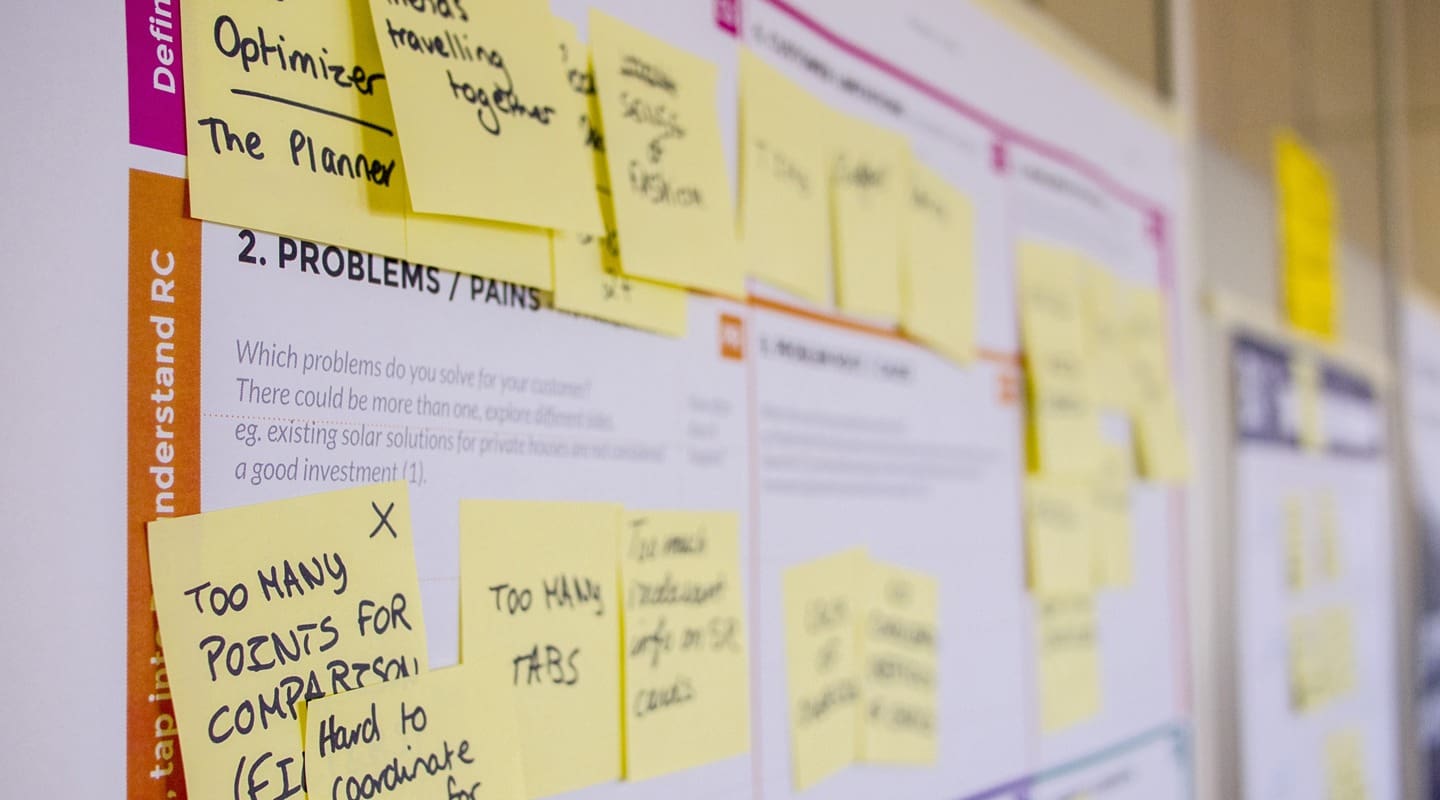 Product management workshop board with sticky notes outlining problems and pains.