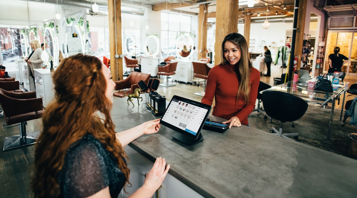 Customer paying with a tablet at a salon. CRM systems help streamline checkout.