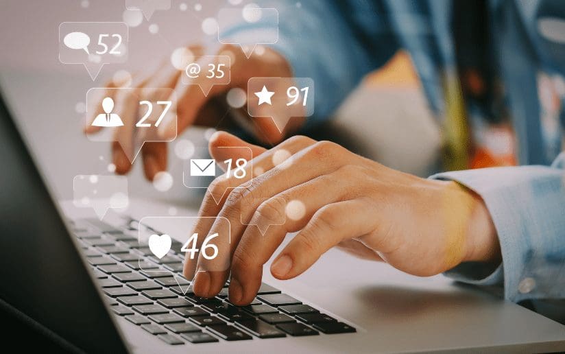 Hands typing on a laptop with social media icons overlayed. B2B content sharing.