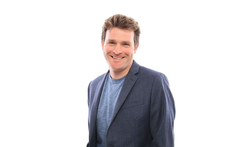 Smiling man in a blue blazer and t-shirt, looking at the camera