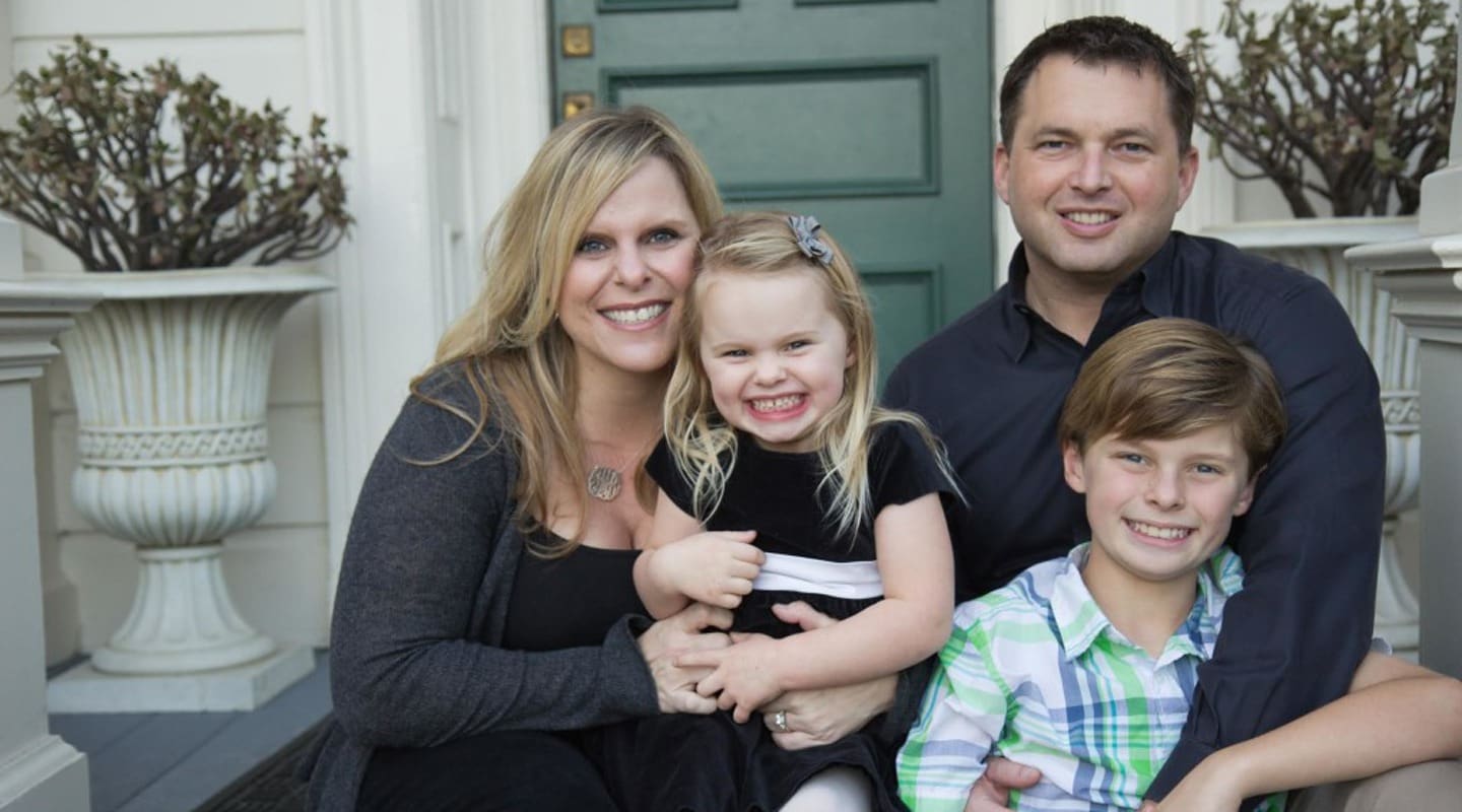 Family portrait of Tricia McKinney, a creative thinker, with her husband and children smiling on a porch.