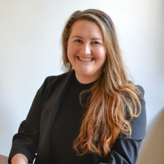 Woman with long brown hair smiles in a black blazer
