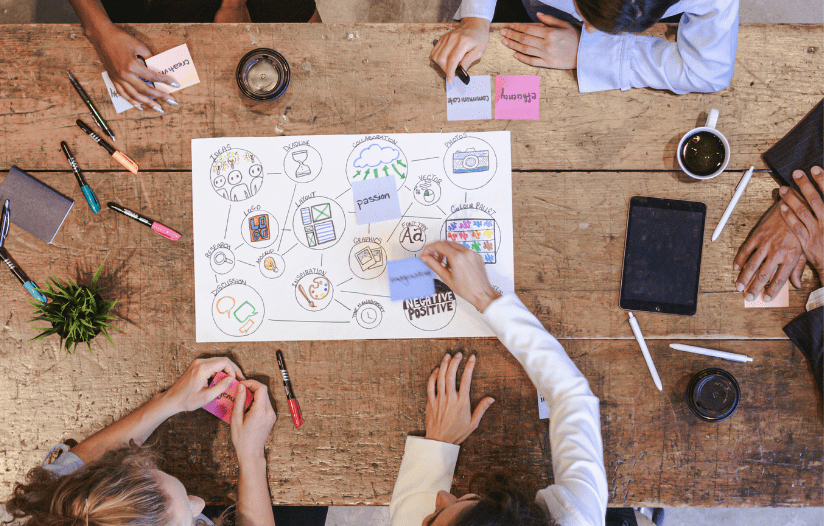 Team brainstorming marketing ideas on a wooden table, including Ideas, Passion, and Collaboration.