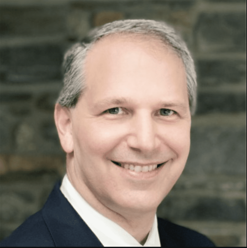 Smiling man in a suit, potentially discussing AI marketing strategies.