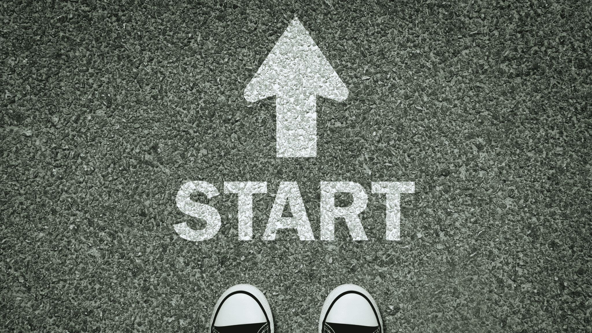 Sneakers facing START on asphalt, symbolizing new beginnings for 2025