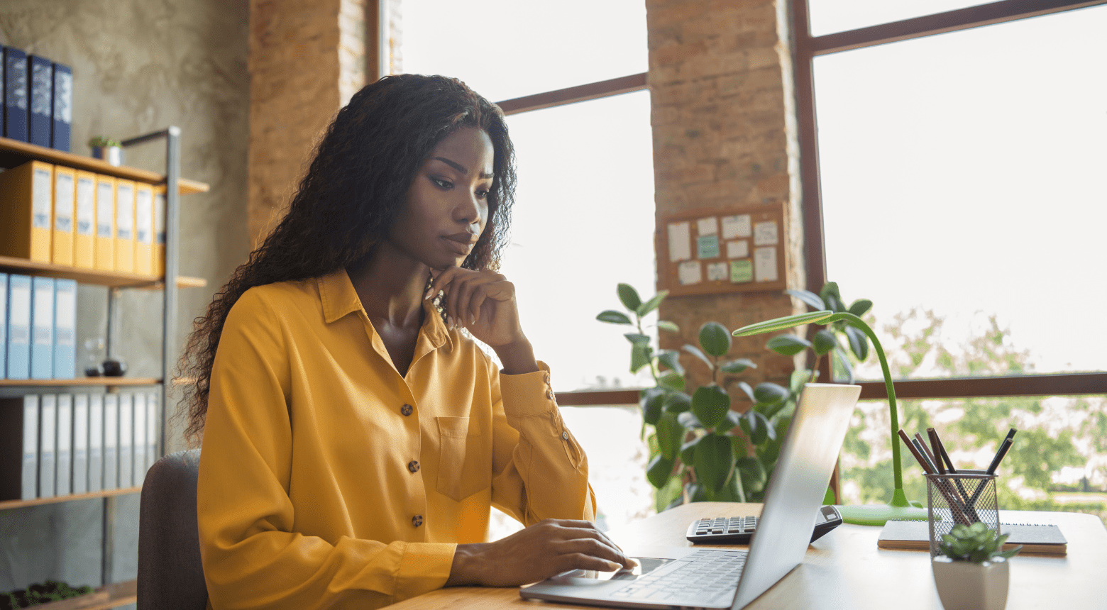 Woman working on laptop at desk, considering marketing consultant for parental leave coverage.
