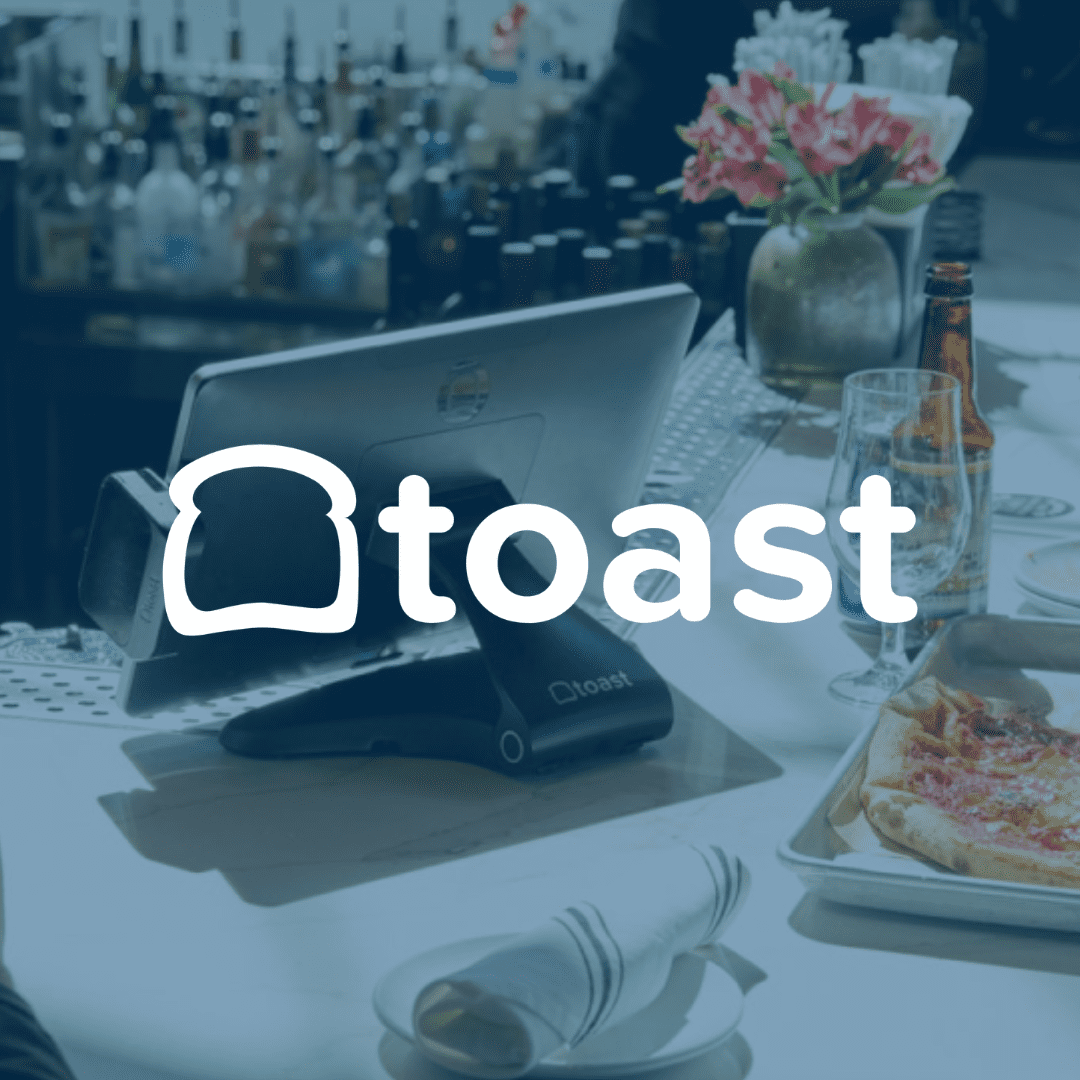 Toast POS system in a restaurant setting with pizza and beer on the bar