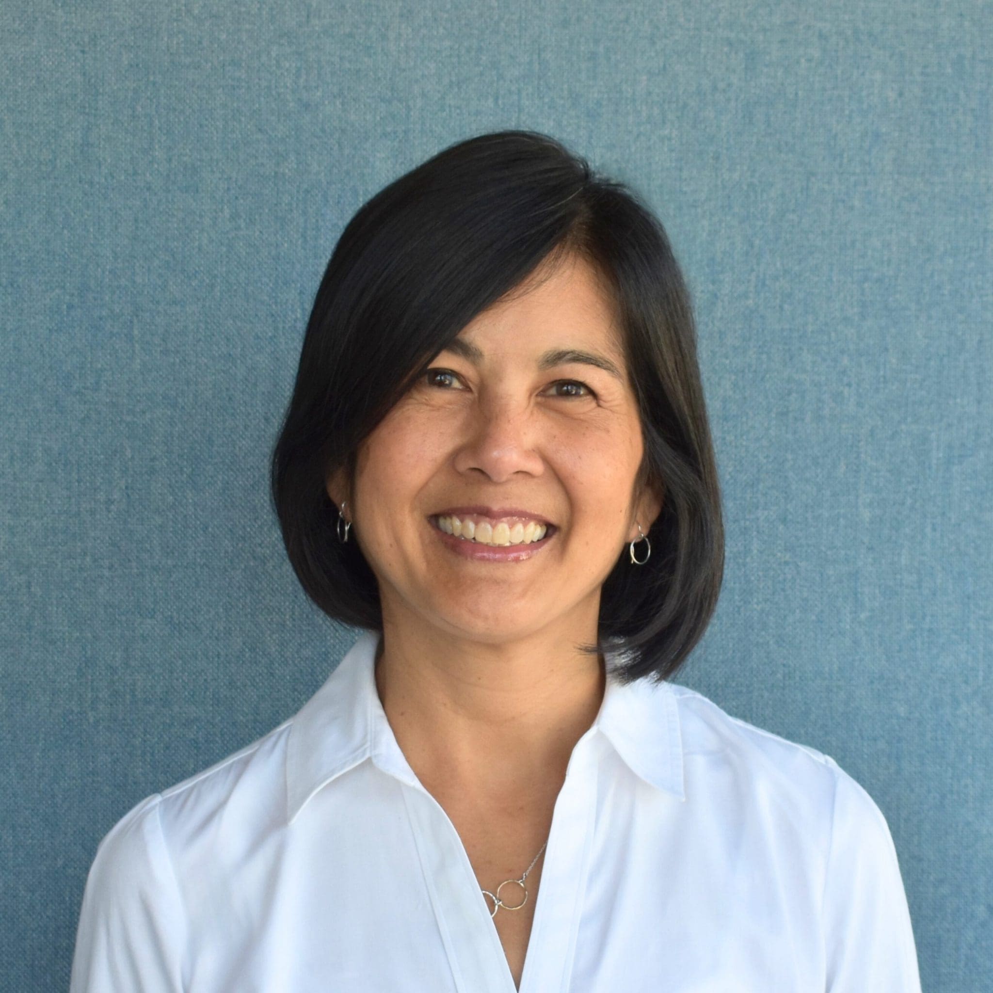 Smiling Asian woman with short black hair wearing a white shirt.