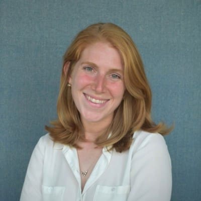 Young woman with red hair smiles, showcasing healthy skin, a benefit of Vitamin C